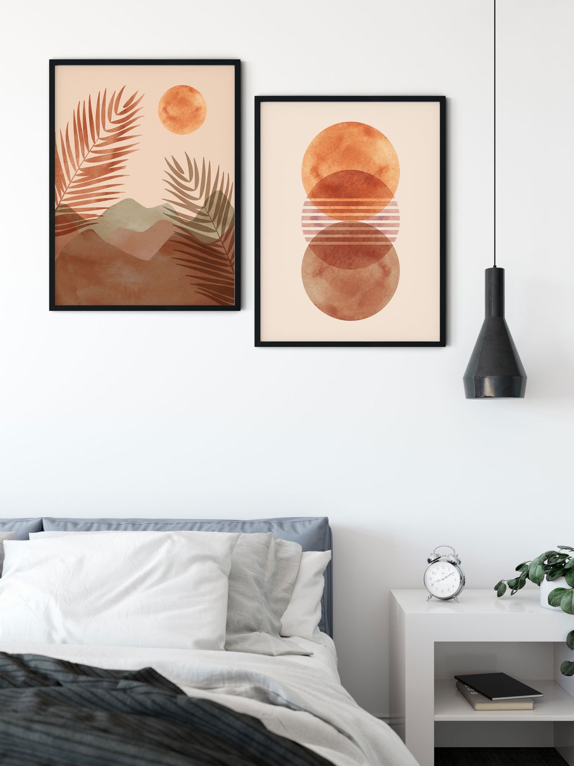 Desert and moon prints grouped above a bed beneath a black pendant light
