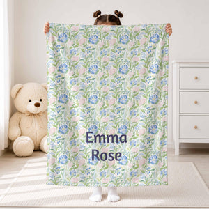 Child holding a sage and blue floral blanket with Emma Rose