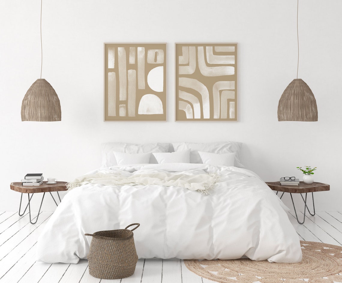 Beige and terracotta abstract pair above a white bed with rattan pendants