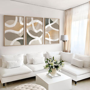 Three beige and grey abstract prints of looping white lines above a white sofa